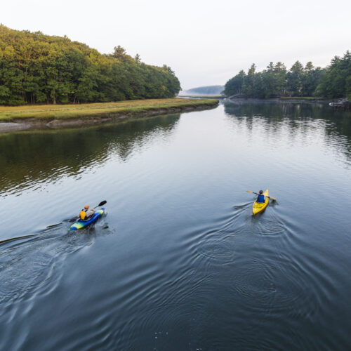 Two kayakers enjoy an early morning paddle on the York River in York, Maine.